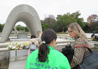 Intern listening to an explanation of the Cenotaph for the A-Bomb Victims by a peace volunteer