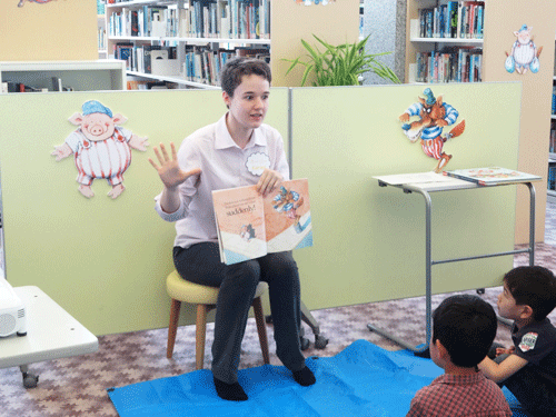 Coordinator for International Relations Ms. Karlee reads a picture book to children