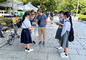 Communicating the peace message to people overseas, and asking questions in English about the purpose of their visit to Hiroshima