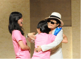 中・高生ピースクラブから折り鶴のレイを受け取り、喜びを表すオノ・ヨーコさん