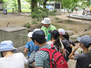 慰霊碑めぐりでピースボランティアの説明を受ける参加者