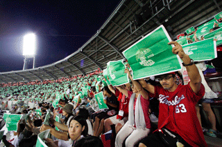 緑色と赤色のピースポスターを用いて原爆ドームと同じ高さに「ピースライン25」を作る観戦客