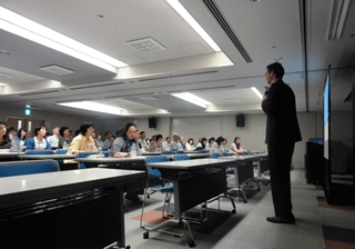 原爆被害を英語で伝える方法について、ネヴィット氏（右）の説明に熱心に耳を傾け、メモを取る参加者