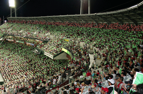 緑色と赤色のピースポスターを用いて原爆ドームと同じ高さに「ピースライン25」を作る観戦客