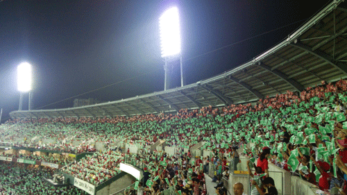 緑色と赤色のピースポスターを用いて原爆ドームと同じ高さに「ピースライン25」を作る観戦客